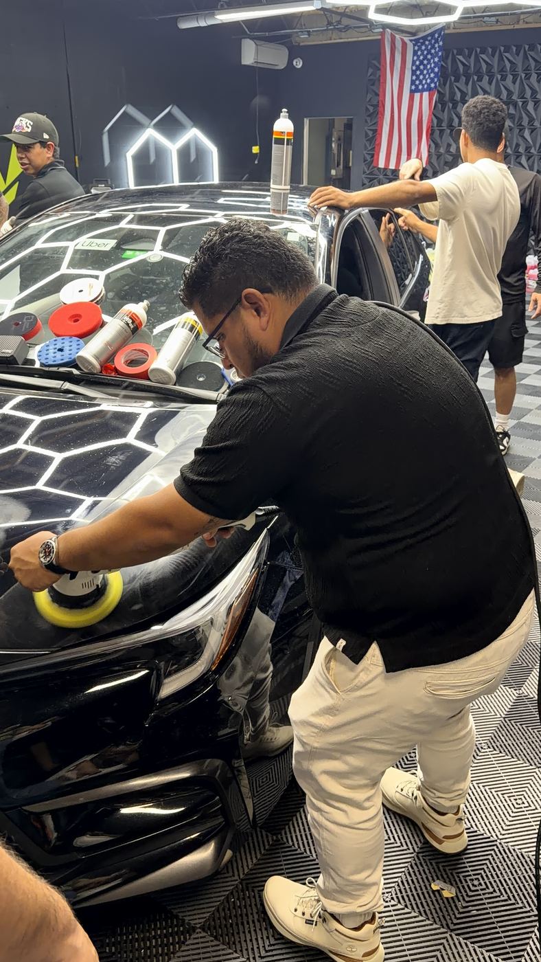 Technician hand-polishing a vehicle headlight