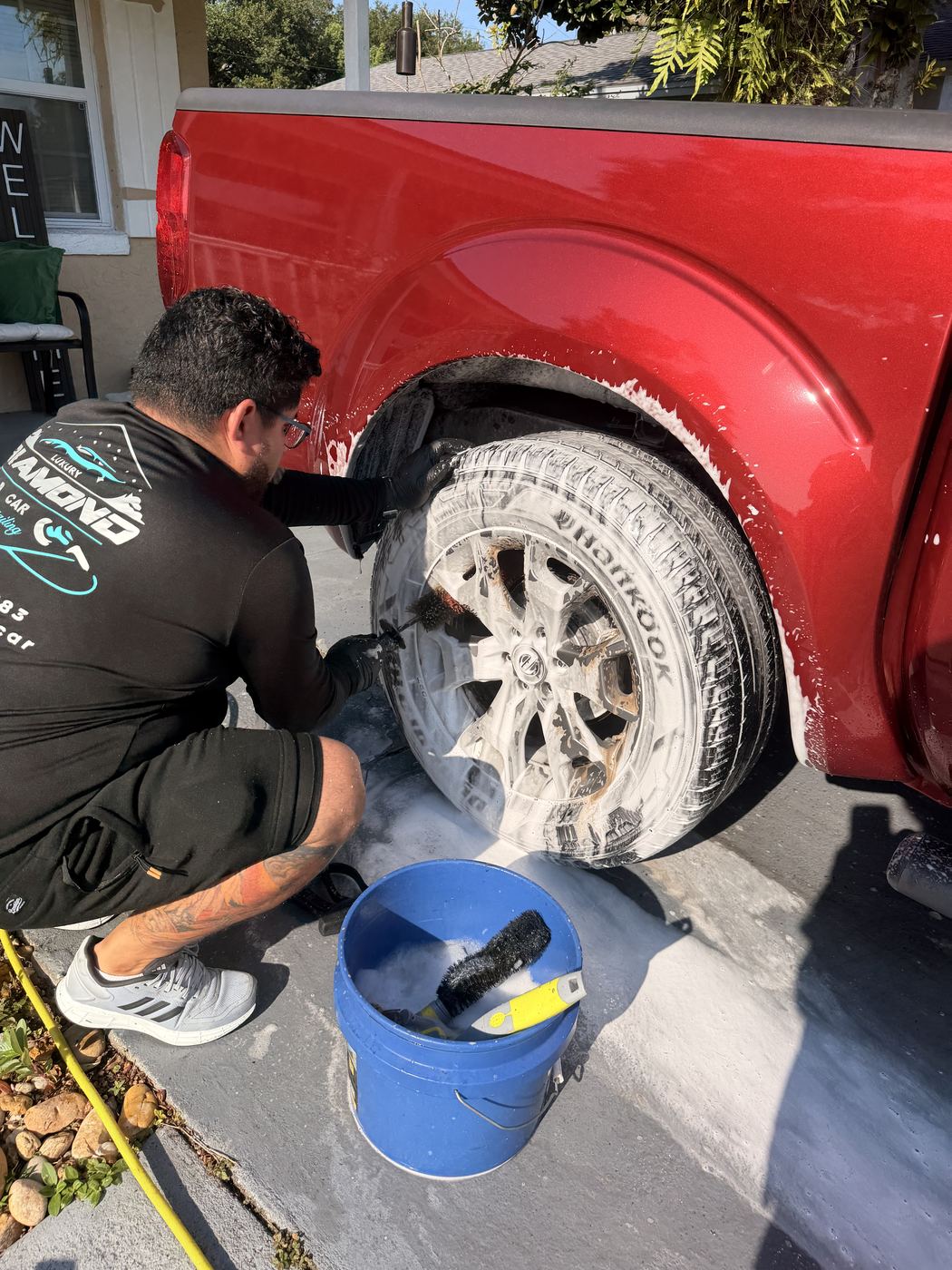 Technician deep-cleaning a truck wheel and wheel well