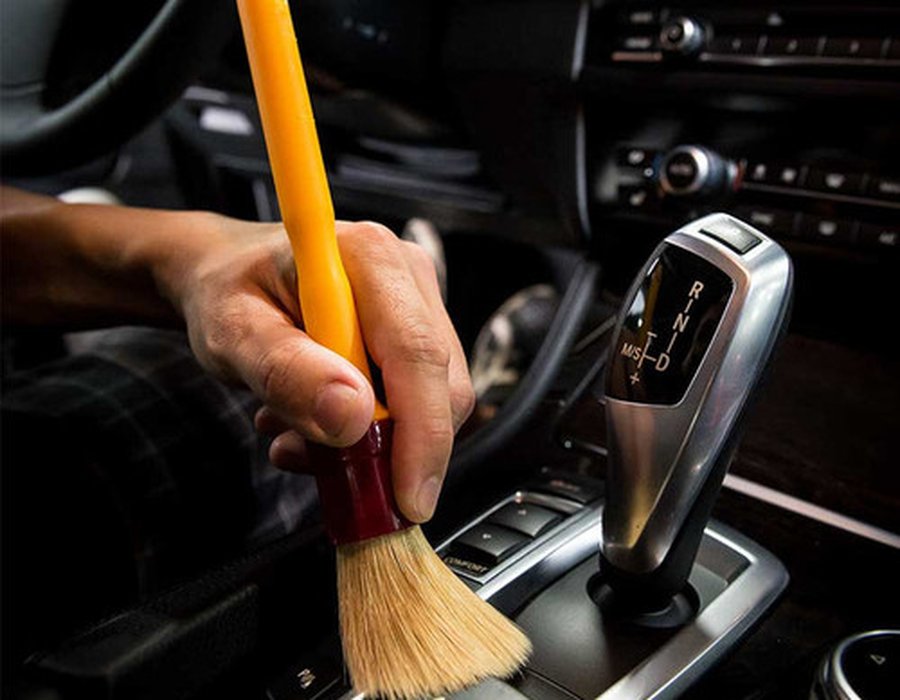 Detail brush cleaning a vehicle's center console and gear shift