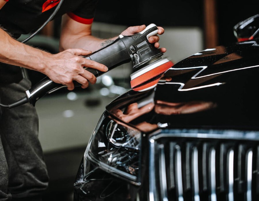 Technician machine-polishing a vehicle hood during paint correction